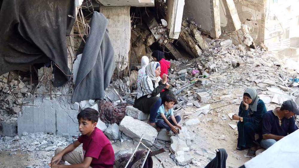 Perempuan dan anak-anak Palestina duduk di reruntuhan rumah di Gaza tengah setelah serangan udara Israel. (AFP)